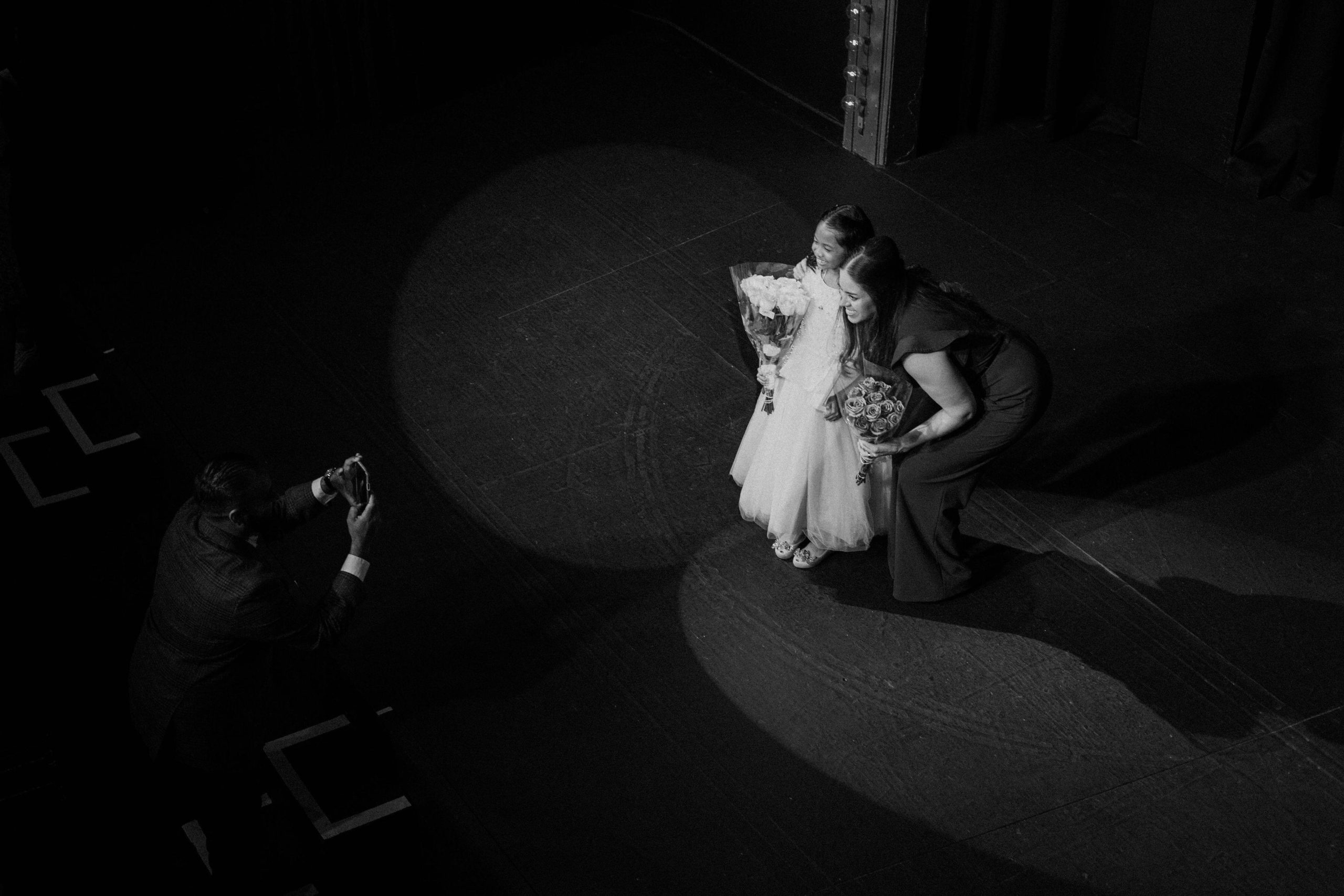 Black and white image of Christina Walker standing with a young girl on a stage after the girl's performance